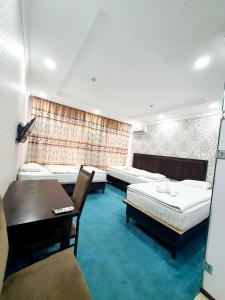 a bedroom with two beds and a desk and a table at Alo Grand Hotel in Eshonguzar