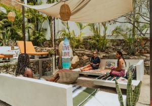 a group of people sitting on benches under an umbrella at Outsite Todos Santos - Formerly Perro Surfero Hotel Boutique in Todos Santos