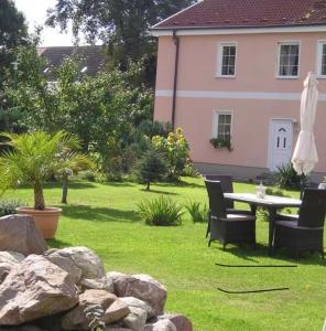 a garden with a table and chairs and a pink house at Lüsser Landsitz in Bad Belzig