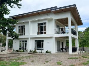 a large white house with a roof at Central 1 Suites in Mambajao
