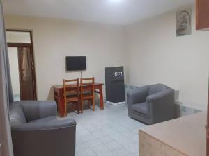 a living room with two chairs and a table and a television at Capri Hills 9 in Mwanza