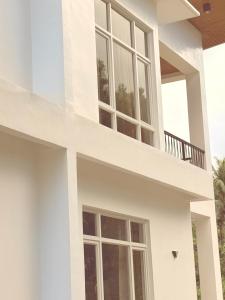 a white house with large windows and a balcony at Central 1 Suites in Mambajao +3 photos