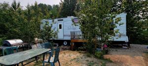 a white caravan parked in a yard next to trees at Le Refuge du Navigateur in Tadoussac