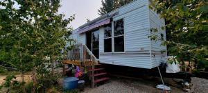 a white tiny house with a porch and a staircase at Le Refuge du Navigateur in Tadoussac