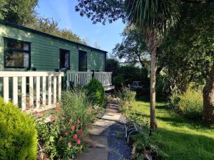 a green house with a white fence in a garden at Maggie's Garden Retreat in Millom