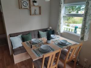 a dining room table and a couch with a table and chairs at Maggie's Garden Retreat in Millom