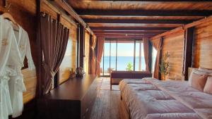 a bedroom with a bed and a view of the ocean at Sunset Moyo Bungalows in Moyo Island