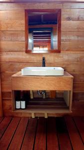 a bathroom sink with a mirror on a wooden wall at Sunset Moyo Bungalows in Moyo Island +71 photos