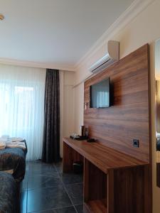 a hotel room with a desk with a television on the wall at Pamukkale Cleopatra in Pamukkale