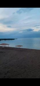 two umbrellas on a beach with the ocean in the background at Этно House in Tong