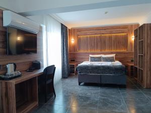 a bedroom with a bed and a desk and a television at Pamukkale Cleopatra in Pamukkale +1 photo