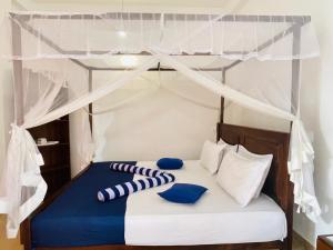 a bed with a canopy with blue and white pillows at Mount Top in Dickwella
