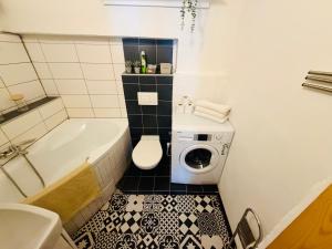 a bathroom with a tub and a toilet and a washing machine at Apartmány pod zvonicí, Vimperk in Vimperk