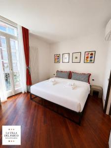 a large white bed in a room with wooden floors at La Villa Del Parco in Monza