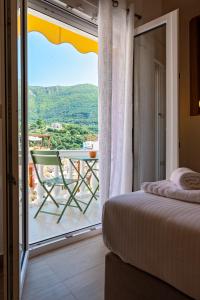 a bedroom with a bed and a balcony with a table at Elysian suite in Parga