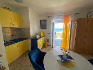 a kitchen with yellow cabinets and a table and a window at Apartments Natali in Sveti Petar