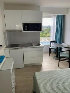 a kitchen with a sink and a table in a room at Studio piscine et vue mer in Trévou-Tréguignec