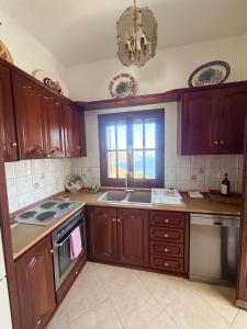a kitchen with wooden cabinets and a sink and a window at Ocean Peak Villa in Kalymnos