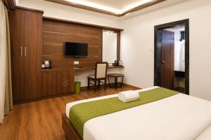 a hotel room with a bed and a tv at Hotel Lemon in Valavanūr