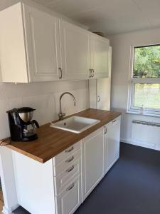 a kitchen with white cabinets and a sink at Sommerhus i Hals in Hals +9 photos