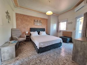 a bedroom with a large bed and a chair at Stella Maris sea front studios in Kanatádhika +20 photos