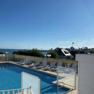 a swimming pool with chairs and the ocean in the background at Studio piscine et vue mer in Trévou-Tréguignec