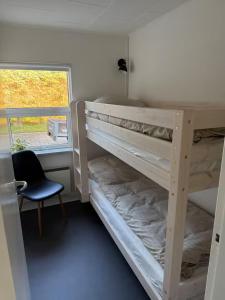 a bedroom with bunk beds with a chair and a window at Sommerhus i Hals in Hals