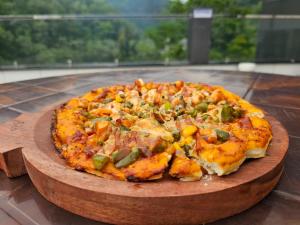 a pizza on a wooden cutting board on a table at Hotel LimeStarow in Bijni