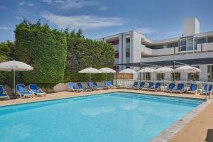 a swimming pool with chairs and umbrellas and a building at Résidence Odalys Aqualia in Balaruc-les-Bains