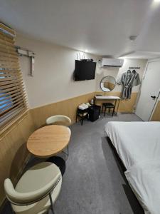 a room with a bed and a table and chairs at T hotel in Seoul