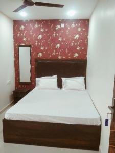 a bedroom with a large bed with a red wall at Hotel Tirumala Vaibhav in Secunderabad