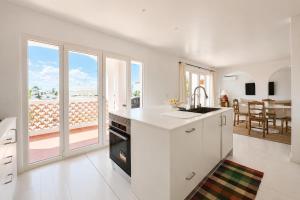 a white kitchen with a view of a balcony at Casa Branca - Caparica in Charneca +16 photos