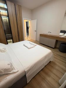 a bedroom with a large white bed and a bathroom at Selez Aparthotel & Residence in Durrës