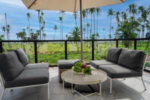 a living room with two chairs and an umbrella and a table at Manao Seaview Pool Villa 33 - 5 Mins Walk To The Beach in Ko Lanta