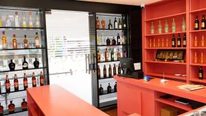 a bar with a red counter and shelves of wine bottles at Hotel Lemon in Valavanūr +17 photos