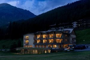 a large building in the mountains at night at Hotel Gampen in Solda