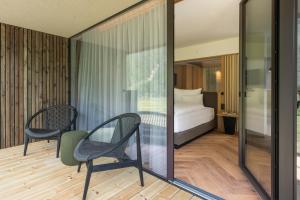a bedroom with a bed and two chairs in a room at Hotel Gampen in Solda