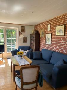 a living room with a blue couch and a brick wall at Hellesbnb in Rømø