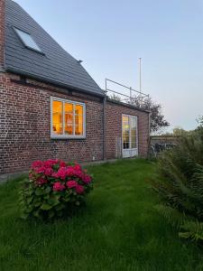 a brick house with pink flowers in a yard at Hellesbnb in Rømø
