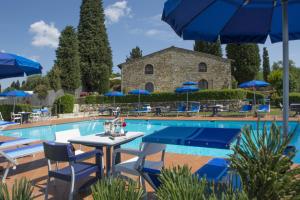 a pool with chairs and tables in it at Hotel Belvedere Di San Leonino in Castellina in Chianti
