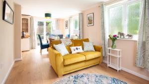 a living room with a yellow couch and windows at Lemon Tree Cottage in Broadway