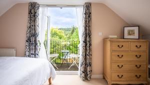 a bedroom with a bed and a door leading to a balcony at Lemon Tree Cottage in Broadway
