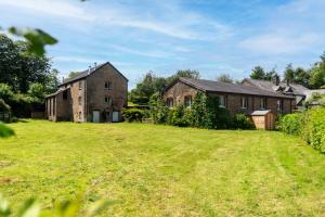 a large grassy yard in front of two brick buildings at The Stables - Old Mill Cottages in Ilfracombe