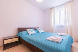 een slaapkamer met een blauw bed en handdoeken bij Apartments Dragica 927 in Medulin