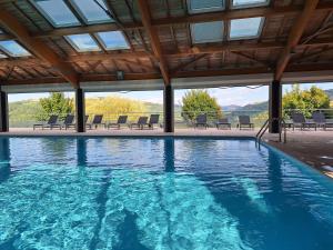 a large swimming pool with chairs and a roof at Les Abeilles in Trébas