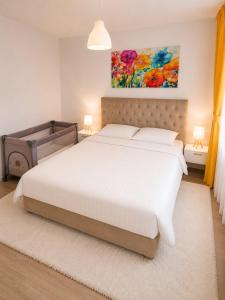 a bedroom with a white bed and a painting on the wall at MM Central Apartment with Parking in Skopje
