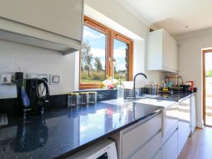a kitchen with black counter tops and a window at Barn Owl Cottage in Bedford