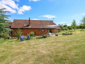 a brick house with two blue chairs in a yard at Barn Owl Cottage in Bedford