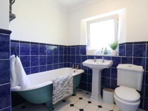 a blue and white bathroom with a tub and a sink at Barn Owl Cottage in Bedford +30 photos