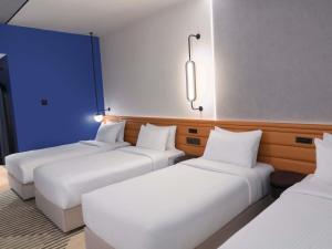 a row of three beds in a room at Novotel Madinah in Medina